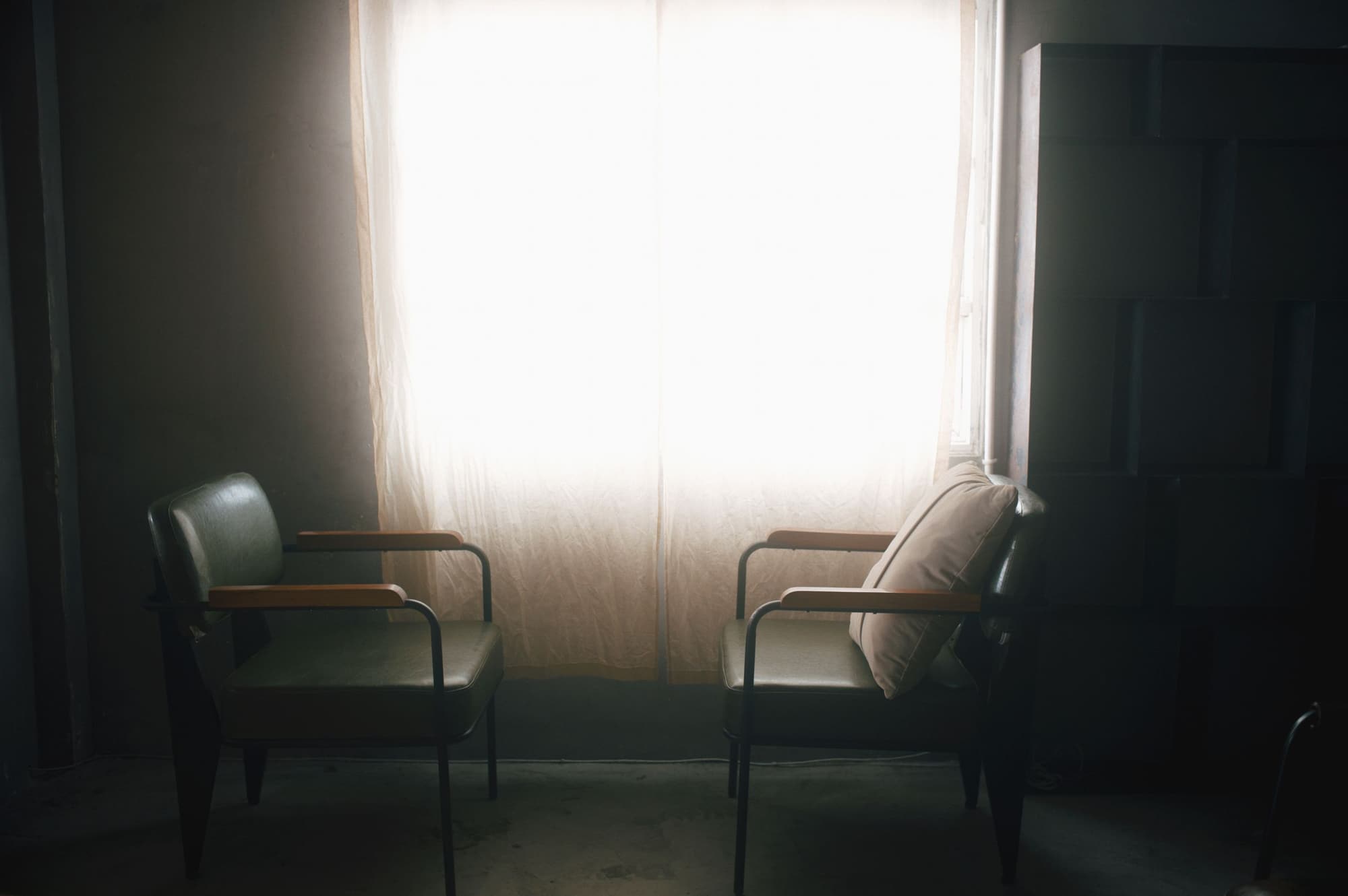 Two armchairs facing each other by a bright window