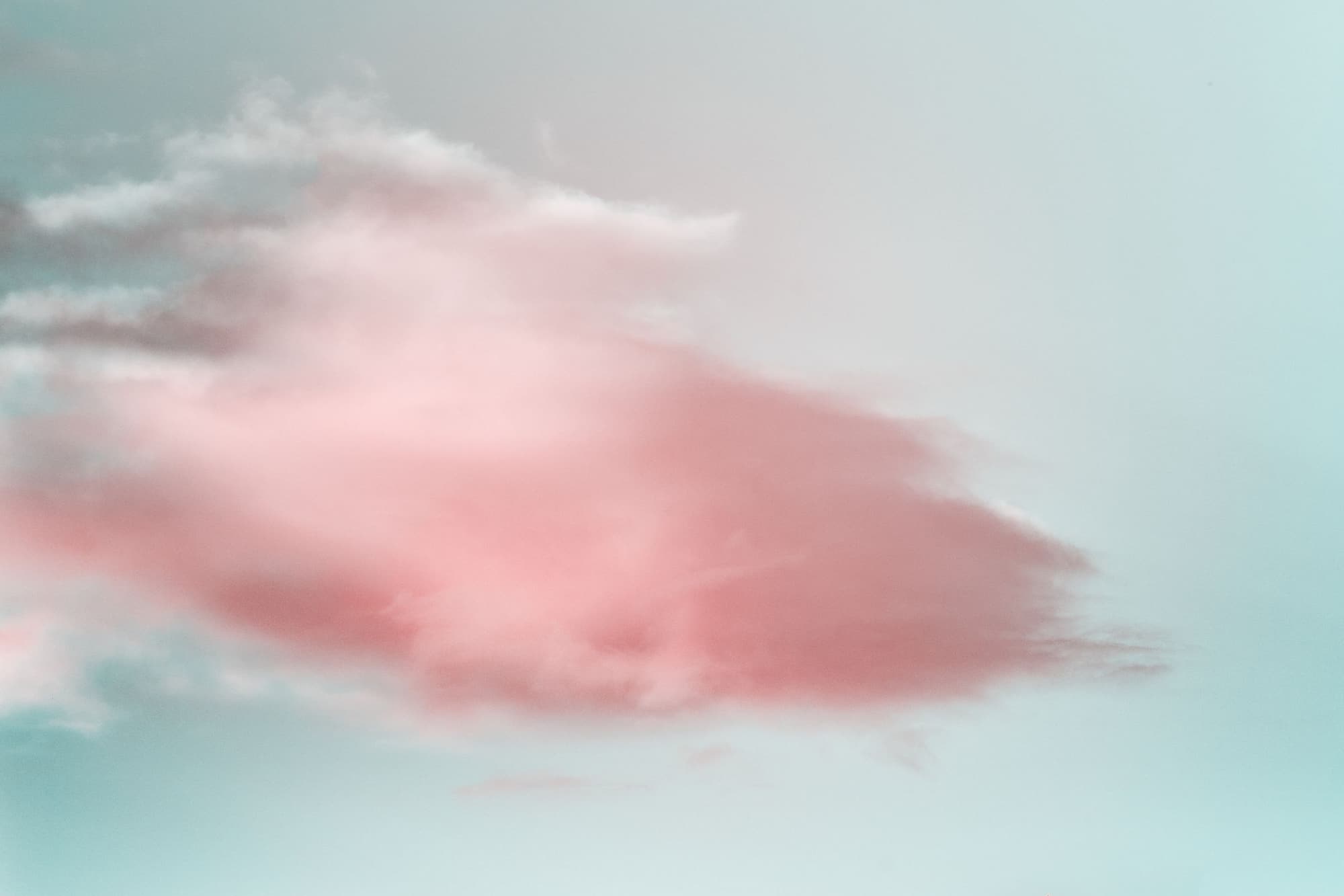 A pink cloud in a pale blue sky