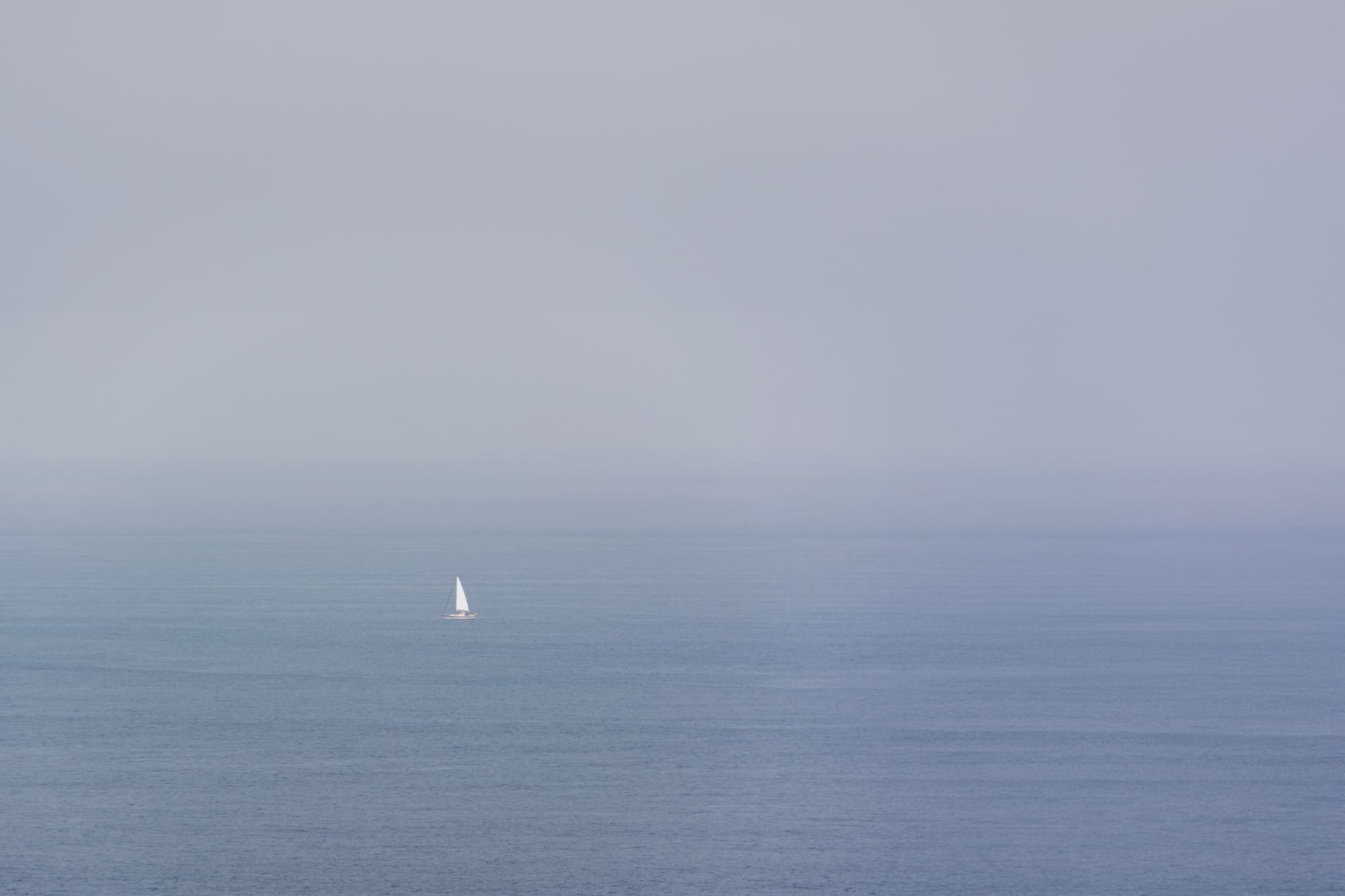 A small sailing boat on a misty sea